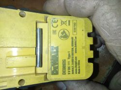 Zbliżenie na żółtą obudowę urządzenia DEWALT z etykietą DE0892G i danymi 9 V DC