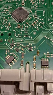 Zbliżenie na zieloną płytkę drukowaną z widocznymi elementami elektronicznymi, w tym układem scalonym ARM.
