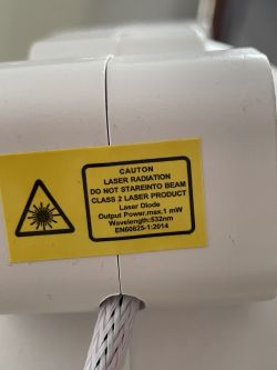 Ostrzeżenie dotyczące promieniowania laserowego na białej zabawce.