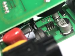 Zbliżenie na płytkę drukowaną z widocznymi elementami elektronicznymi, takimi jak kondensatory i układ scalony.