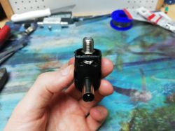 Adapter antenowy trzymany w ręku na tle warsztatowym