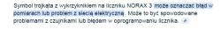 Zrzut ekranu tekstu wyjaśniającego znaczenie symbolu trójkąta z wykrzyknikiem na liczniku NORAX 3.