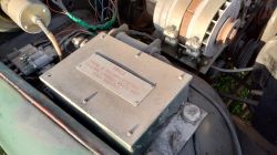 Komora silnika z alternatorem i metalową skrzynką z tabliczką „UWAGA”