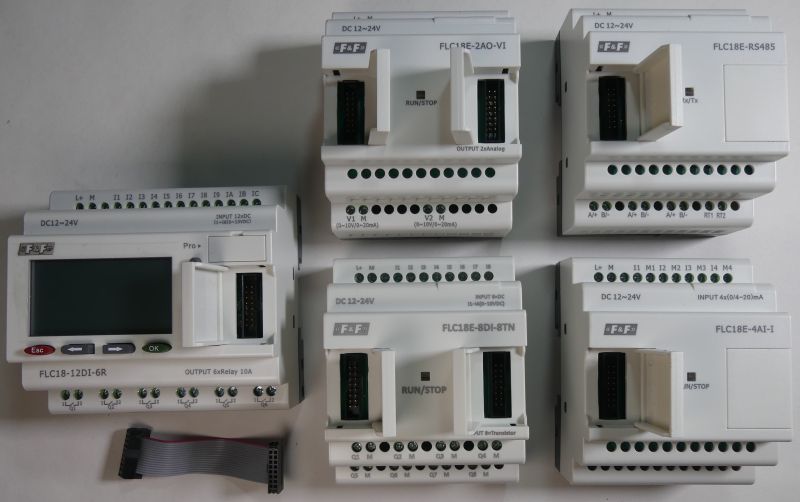 Zestaw programowalnych sterowników logicznych (PLC) F&amp;F wraz z modułami rozszerzeń i przewodem połączeniowym.