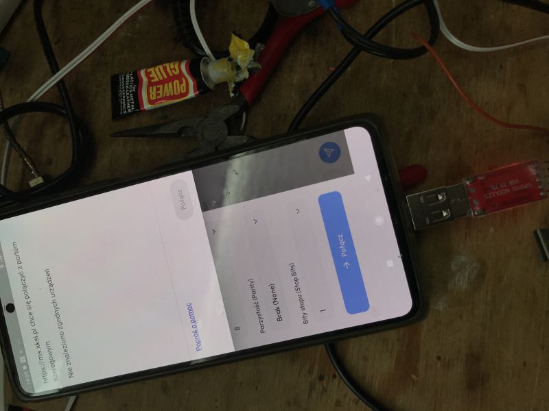 Phone on a workbench showing UART connection settings with a blue “Connect” button