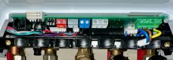 View inside a boiler control panel with colorful wires and connectors.