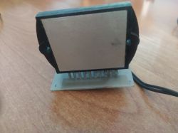 Czarny element elektroniczny z metalową płytką, osadzony na małej płytce z pinami