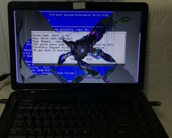 Laptop Dell z pękniętym ekranem i kolorowymi pasami; widoczny komunikat błędu na niebieskim tle