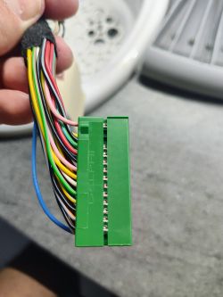 Zielona kostka z kolorowymi przewodami elektrycznymi, na szarym tle.