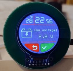 Okrągły wyświetlacz TFT z czasem, temperaturą i alarmem „Low voltage! 2.8 V” oraz ikonami przycisków