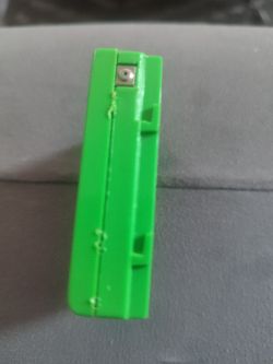 Zielona obudowa akumulatora z widocznym metalowym złączem.