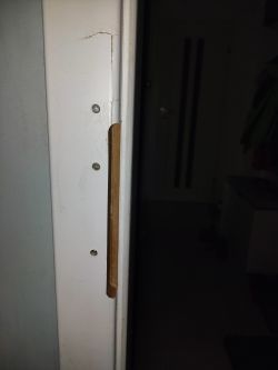 Close-up of a door frame repair, showing screw holes and filler marks.