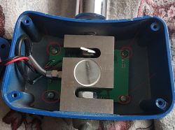 Wnętrze obudowy elektronicznej z zaznaczonymi śrubami.