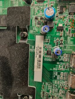 Zbliżenie płyty głównej z radiatorem i kondensatorami; etykieta z kodem 18-65UA6605C-MA1