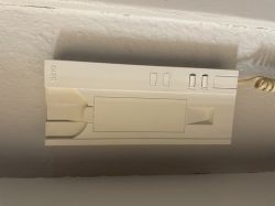 White intercom on a wall with several buttons and a coiled cable on the side.