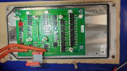 Płytka PCB w metalowej obudowie z tranzystorami mocy, śrubami i czerwonymi przewodami