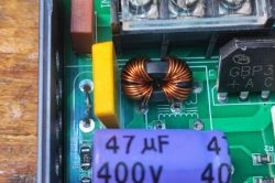 Close-up of a PCB with common-mode choke, bridge rectifier, and capacitor.