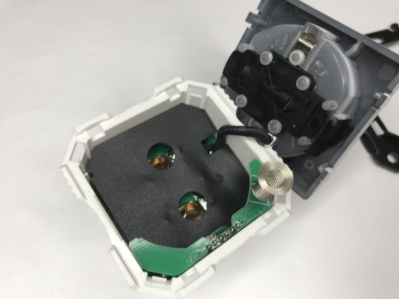 Disassembled in-wall socket showing PCB, wire, and a spring coil antenna inside the housing