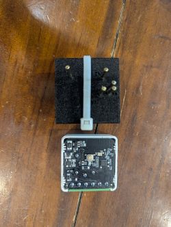 Circuit board in a white housing and black foam block with metal pins on a wooden table