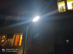 Lampa uliczna świecąca w nocy z widocznym promieniowaniem światła.