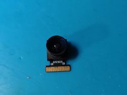 Camera module with lens and electronic connector on a blue background.