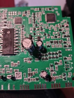 Zbliżenie na zieloną płytkę drukowaną z różnymi komponentami elektronicznymi.