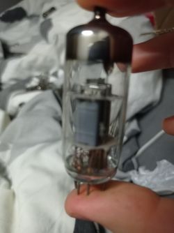 Zbliżenie na lampę elektronową trzymaną w palcach na tle pościeli