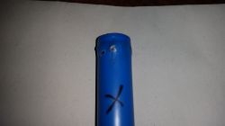 Blue battery with markings and a cross on the casing.