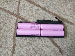 Cztery ogniwa cylindryczne Samsung INR18650-35E zamontowane w plastikowej ramce na dywanie.