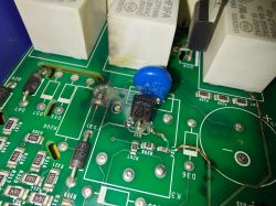 Uszkodzona płytka drukowana z widocznymi przepalonymi ścieżkami i elementami elektronicznymi.
