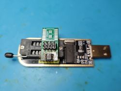 CH341A programmer with SOIC-8 adapter and soldered flash memory on blue background