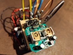 Electronic circuit board with attached wires and components on a wooden block.