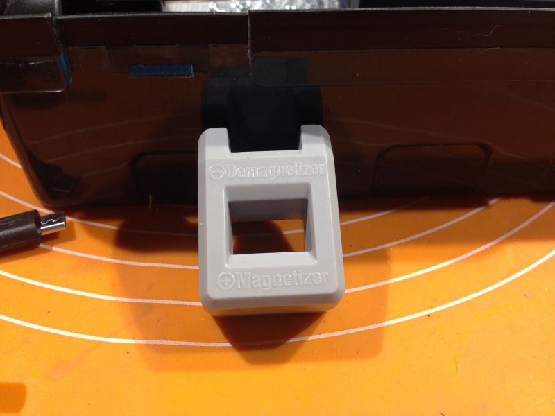 Szary przyrząd do magnesowania na pomarańczowej macie