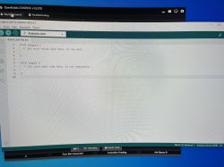 Zrzut ekranu interfejsu Arduino IDE z pustym szkicem kodu.