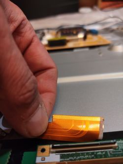 Ręka trzymająca taśmę elektroniczną z zaklejonymi pinami.