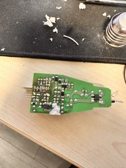 Printed Circuit Board Inside an LED Bulb Printed circuit board with electronic components lying on a wooden table.