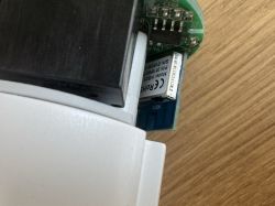 Close-up of a WB2S electronic module installed inside a plastic enclosure on a wooden surface.