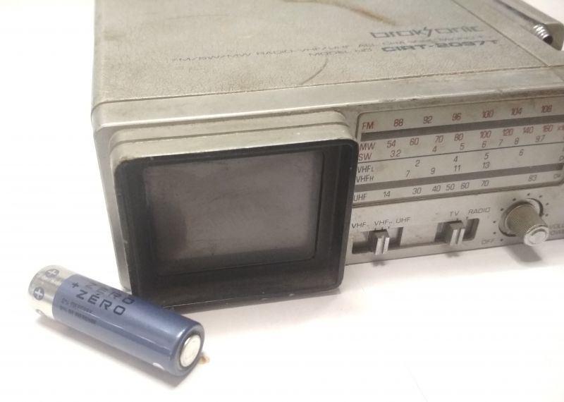 Mini telewizor Broksonic CIRT-2097T obok baterii AA