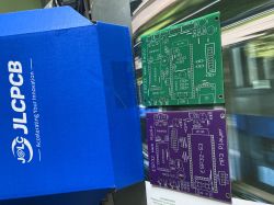 Two ESP32 PCBs next to a blue JLCPCB box