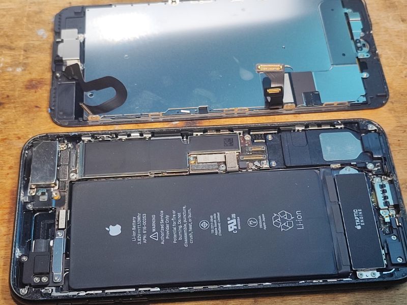 iPhone Disassembly for Battery Replacement Open iPhone with exposed battery and detached screen.
