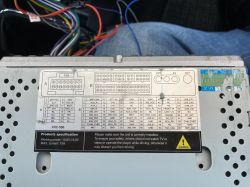Tabliczka z oznaczeniami z tyłu radia z Androidem, model XRC-556, z przewodami w tle.