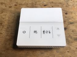 Touch Panel Room Thermostat White room thermostat with touch buttons on a wooden background.