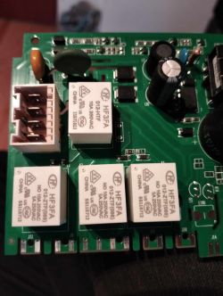 Zbliżenie na płytkę elektroniczną z widocznymi przekaźnikami i komponentami.