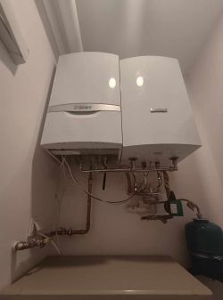 Dwa kotły Vaillant zamontowane na ścianie z rurami i elementami instalacji hydraulicznej.