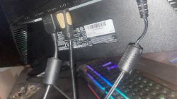 Zbliżenie na tył monitora z podłączonymi kablami, w tym HDMI i VGA.