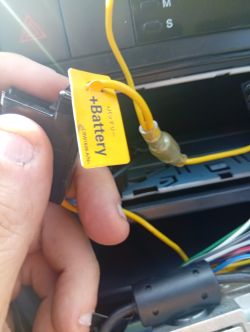 Zbliżenie na żółty przewód z etykietą „+Battery” podłączony do radia samochodowego