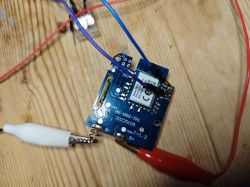 CB3S Module on PCB CB3S module mounted on a blue PCB with connected wires on a wooden surface.