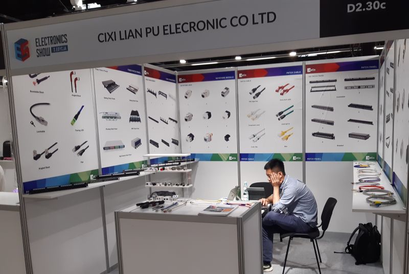 Stoisko firmy Cixi Lian Pu Electronic Co Ltd na targach, z siedzącym pracownikiem.