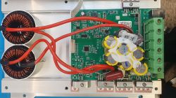 Wnętrze regulatora MPPT: płytka PCB, dwa miedziane dławiki i zielona listwa zaciskowa