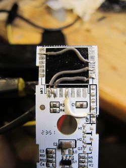 White PCB with electronic components and wires soldered on top of the board.